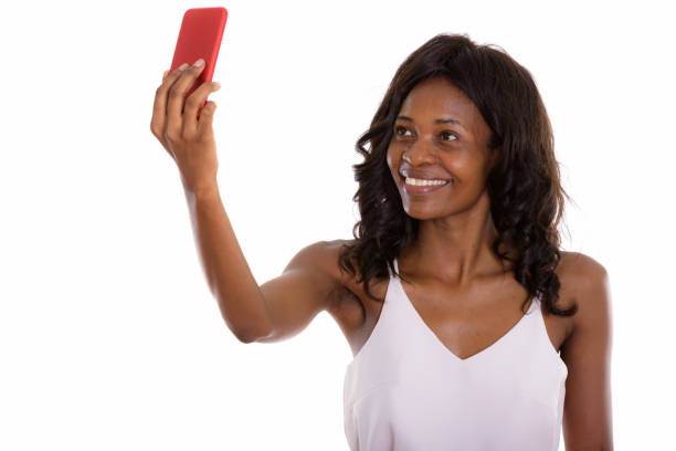 携帯電話で selfie 写真を撮るながら笑顔若い幸せ黒アフリカ実業家のスタジオ撮影 - businesswoman black african descent studio shot ストックフォトと画像