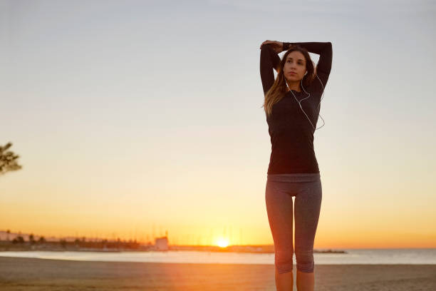 istock Confident young woman stretching arm at beach 670410854