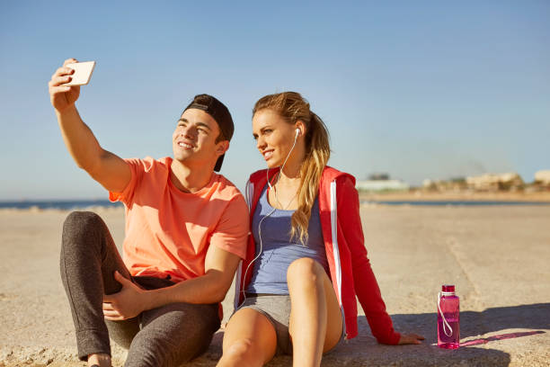 istock Fit couple taking selfie with smart phone at beach 670411048