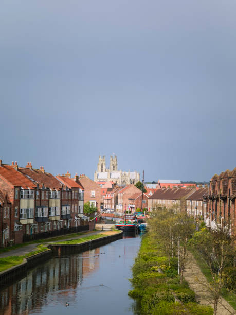 istock Ancient minster as viewed from the canal flanked by townhouses in spring. 670411352