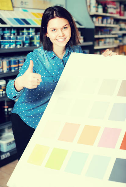 istock smiling female customer examining color scheme variants in paint store 670411414