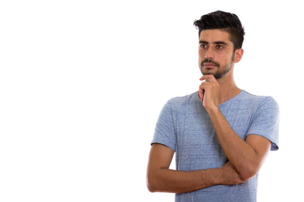 Studio shot of young Persian man thinking while looking at distance horizontal shot