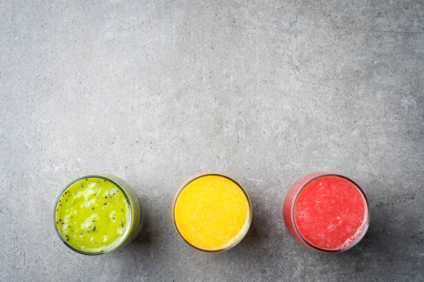 istock Glasses of fresh juice on gray stone table 670414714
