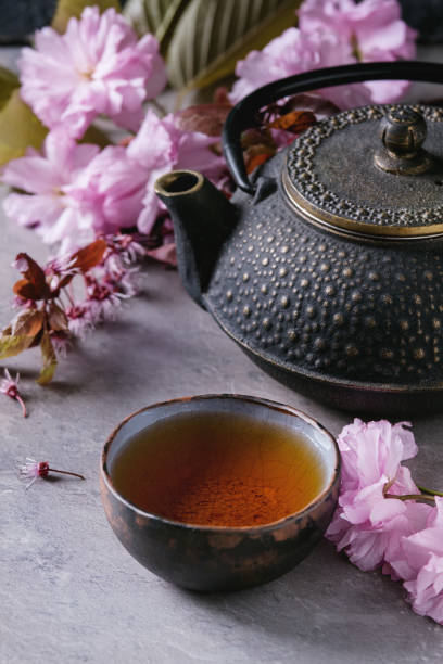 istock Teapot and cup of tea with blossom branch 670421438