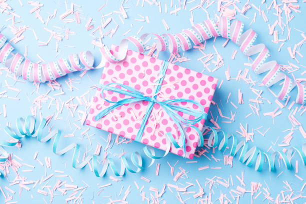 istock Birthday background with pink dotted gift box, serpentine and confetti on blue background 670421926