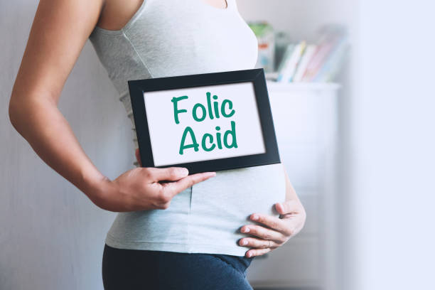 Pregnant woman holds whiteboard with text message - FOLIC ACID. Pregnant woman holds whiteboard with text message - FOLIC ACID. Pregnancy, parenthood, preparation and expectation concept. Close-up, copy space, indoors. board eraser photos stock pictures, royalty-free photos & images