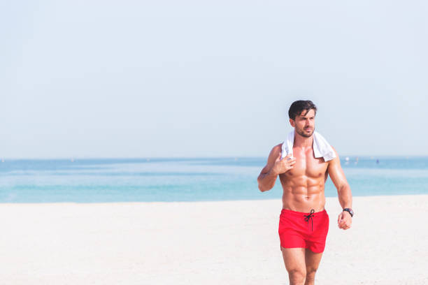 mann zu fuß in der nähe eines strandes - beach shorts stock-fotos und bilder