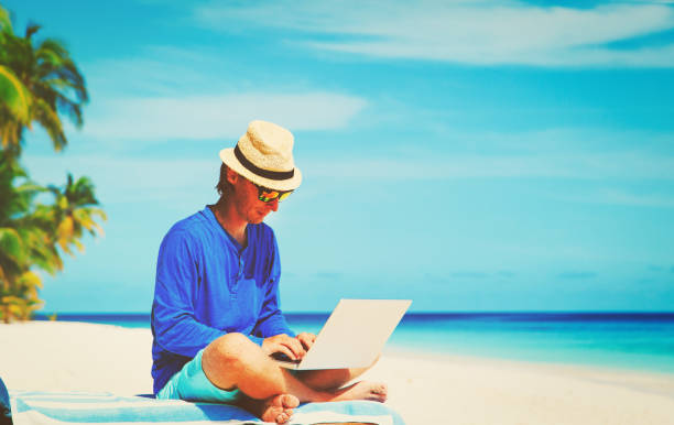 istock man with laptop on tropical beach 670434744