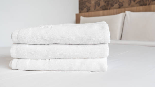 istock Three white laundered fluffy towels on white bed 1 670443242