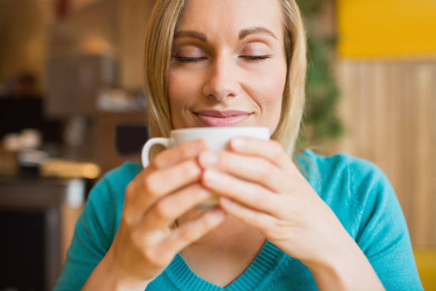 istock Young woman holding coffee cup with eyes closed 670447726