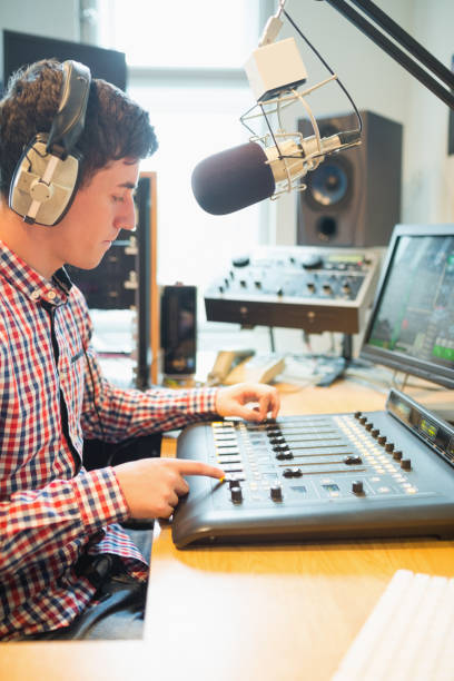 istock Radio host wearing headphones operating sound mixer 670448986