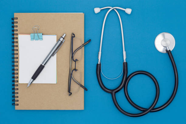 istock Stethoscope with notebook ,pencil, white paper ,coffee cup,glasses on blue background,Medical background concept. 670450680
