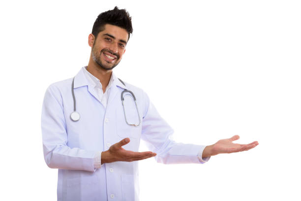 istock Studio shot of young happy Persian man doctor smiling while showing something 670467530