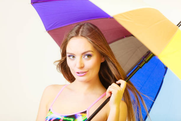 Woman cheerful summer girl standing under colorful rainbow umbrella, Attractive female long hair model. Forecasting and weather season concept