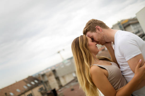 istock Romantic couple in love kissing on rooftop 670495108