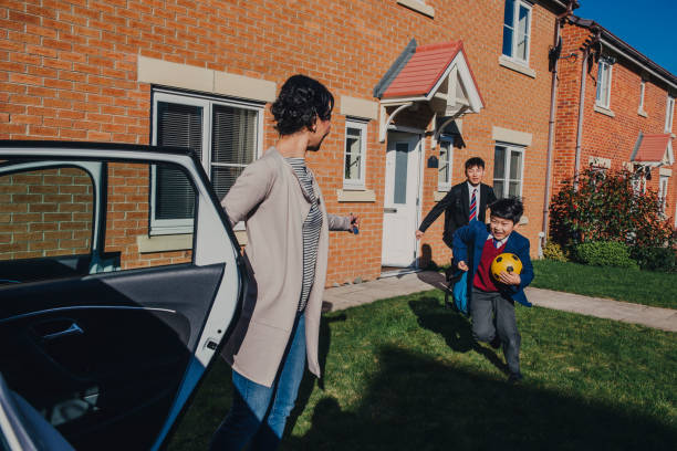 Chinese Brothers Rushing to School! Two Chinese brothers running into the car to get to school as they are late. Not forgetting their soccer ball and school supplies. northern europe family car stock pictures, royalty-free photos & images