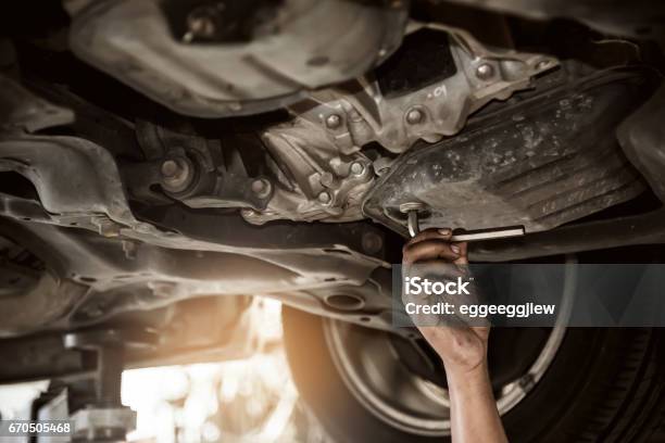 Close Up Of Mechanic Man Hand At Below Of A Car Examining For Change Engine Oil At The Garage Stock Photo - Download Image Now