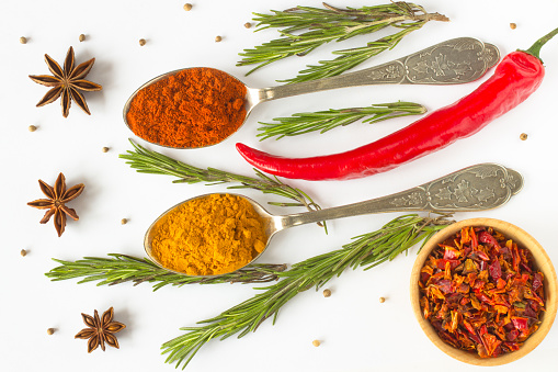 Bowl with aromatic paprika powder and fresh bell peppers on grey wooden table
