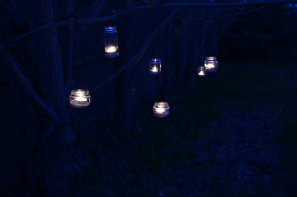 istock night scene candles in jars hanging on tree branches 670520842
