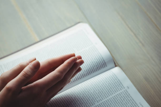 Woman praying with her bible Woman praying with her bible on table methodist stock pictures, royalty-free photos & images