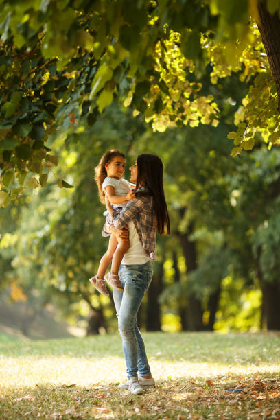 istock Mother holding her daughter and playing around the park 670524488