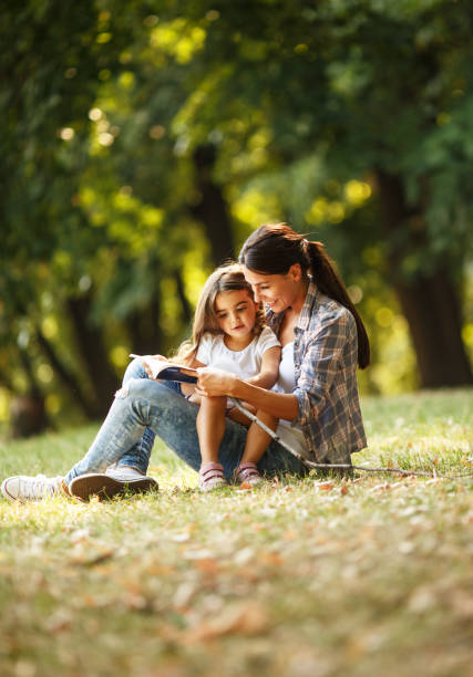 mother and daughter relaxing in park. - reading outside imagens e fotografias de stock