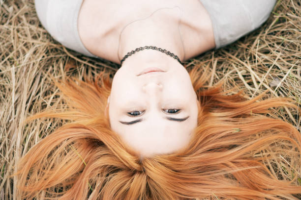 istock Sleeping girl with red hair on the lawn 670525232