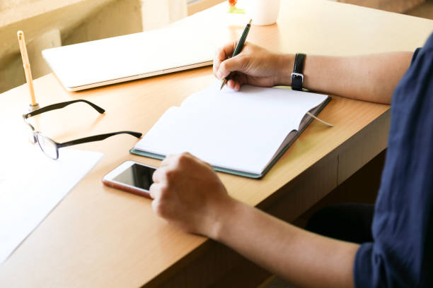 istock someone is going to writing something to note on wooden desk 670528932