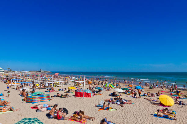 LISBON, PORTUGAL - JUNE 22, 2013: People sunbathing on sandy Atlantic beach in Carcavelos town, Lisbon district, Portugal