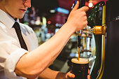 Bartender holding beer glass below dispenser tap