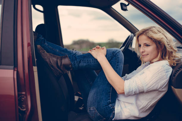 istock Cute blonde woman posing in car interior 670543734