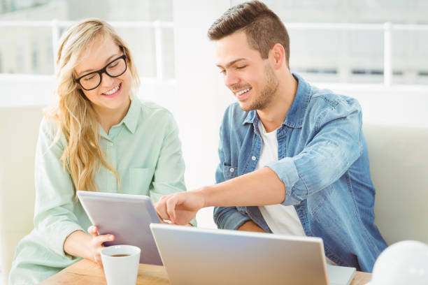istock Smiling woman discussing with man while holding digital tablet 670543986