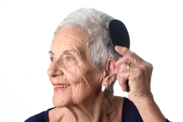 istock Senior woman combing her hair on white background 670554322