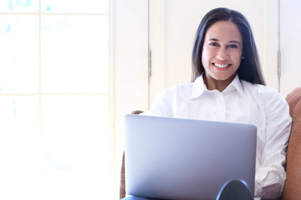 istock Hispanic Female Millennial Sitting On Couch Working On Laptop Computer 670560518