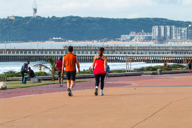 DURBAN, SOUTH AFRICA - APRIL 18, 2017: Many unknown people on paved beachfront promenade against piers and the Bluff in Durban, South Africa