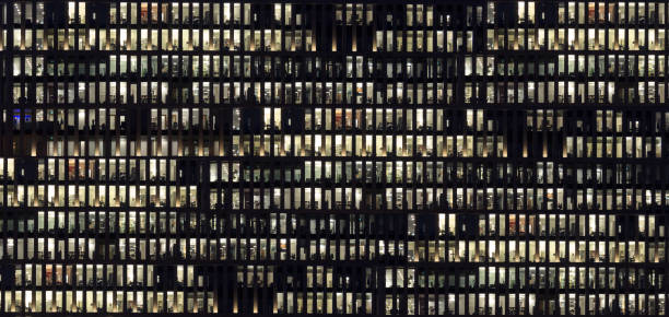 istock modern office building facade, people working at night 670573526
