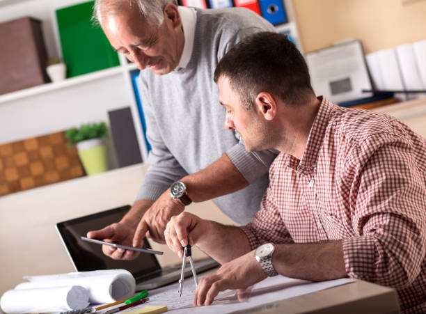 istock Senior and young architect working together on a project in the office 670577392