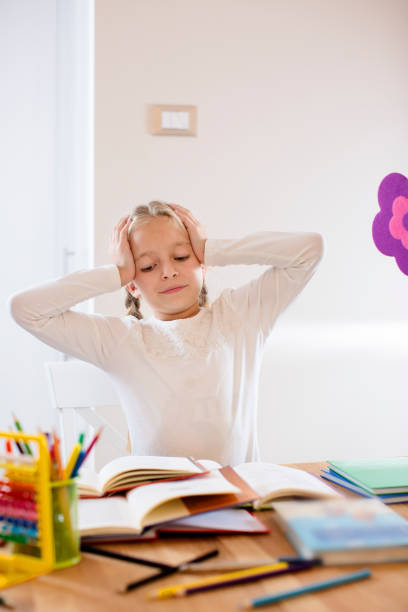 istock Tired cute blond schoolgirl in stress working homework 670579042