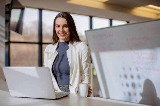 istock Smiling business woman working on computer and drinking coffee 670585336