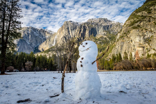 boneco de neve no vale de yosemite, durante o inverno com upper yosemite falls em fundo - parque nacional de yosemite, califórnia, eua - yosemite national park winter waterfall california - fotografias e filmes do acervo