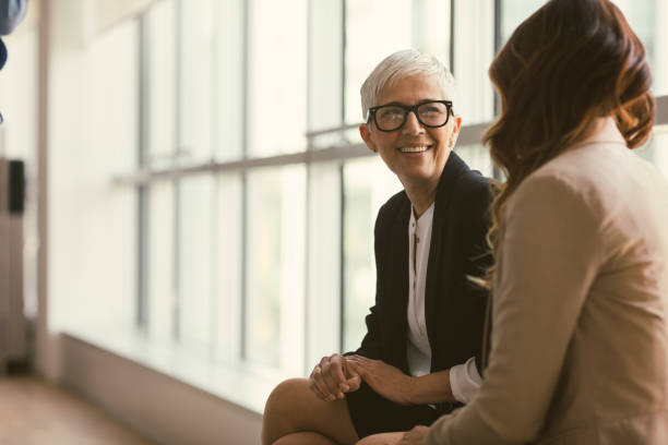 Business people in the office Businesswomen working in the office. Sitting and talking. Focus on mature woman serious talk stock pictures, royalty-free photos & images