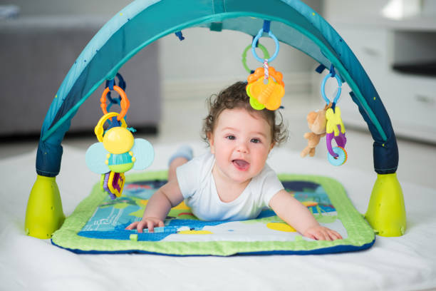 babyjongen, glimlachen en te spelen met speelgoed binnen kinderbox - babybox stockfoto's en -beelden