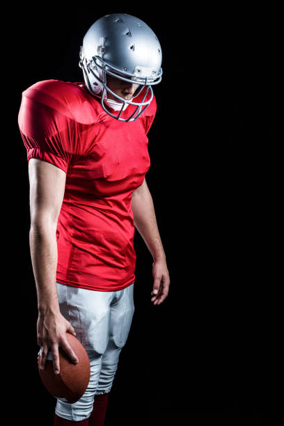 istock American football player with ball looking down 670596866