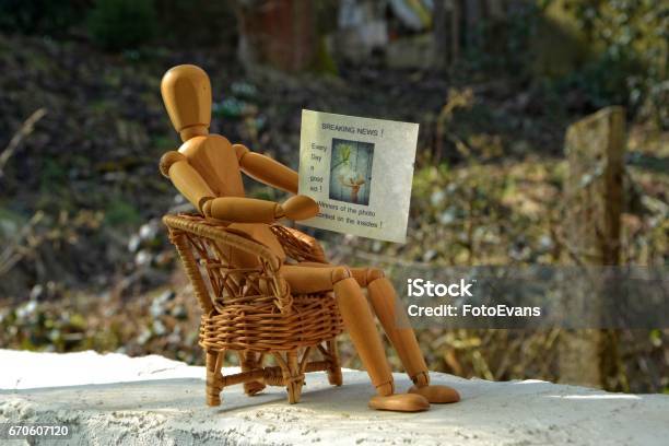 Wooden Figure Sitting On Chair And Reading Newspaper Stock Photo - Download Image Now