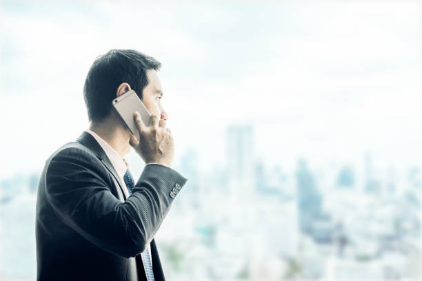 istock Businessman using mobile phone looking through office window to see cityscape building outside,Business vision concept,imgae tone filter 670613930