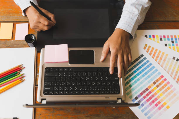 istock freelance graphic designer using digital tablet, computer, man working with color swatch catalog samples for selection - Creativity Editor Ideas Designer Concept 670614298