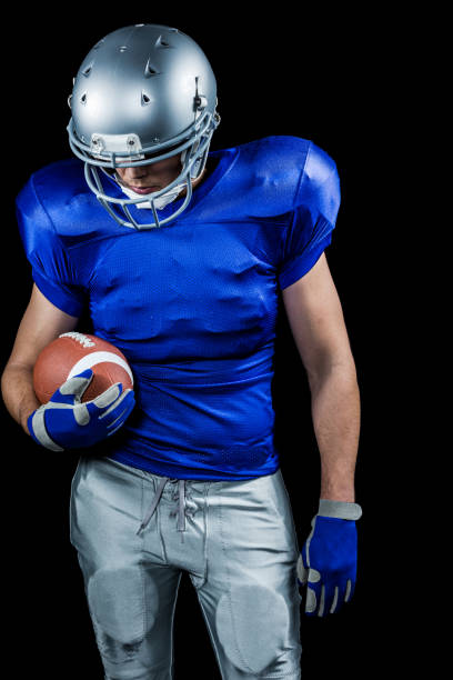 istock American football player looking down while holding ball 670625626