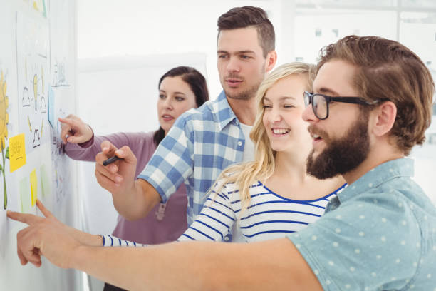 istock Business people discussing at wall with sticky notes and drawings 670625812