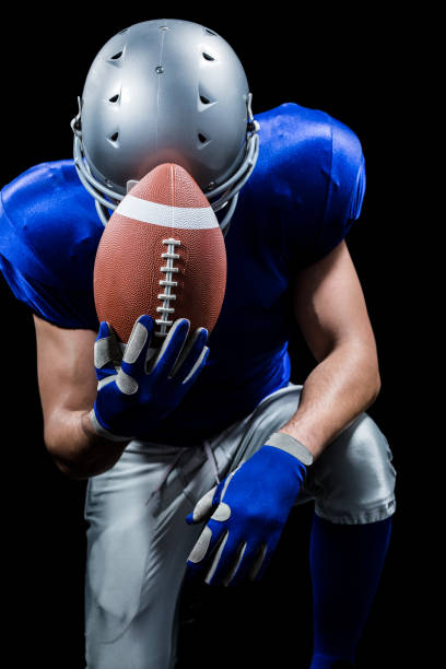 istock Upset American football player kneeling while holding ball 670628008