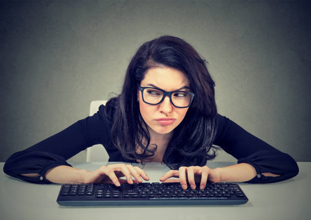 istock Crazy looking nerdy woman typing on the keyboard wondering what to reply plotting a revenge 670631352